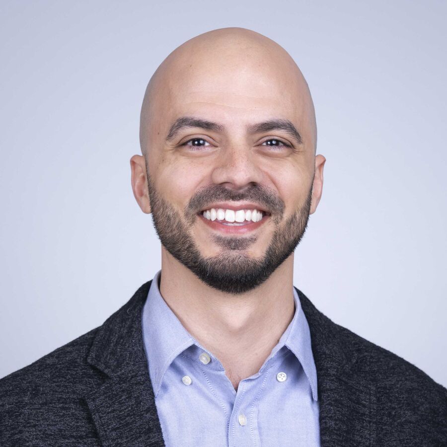 Professional headshot of a smiling bearded man in a navy blazer