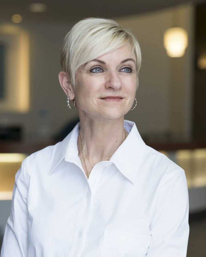 Woman with short blonde hair in a white shirt in a bright lobby