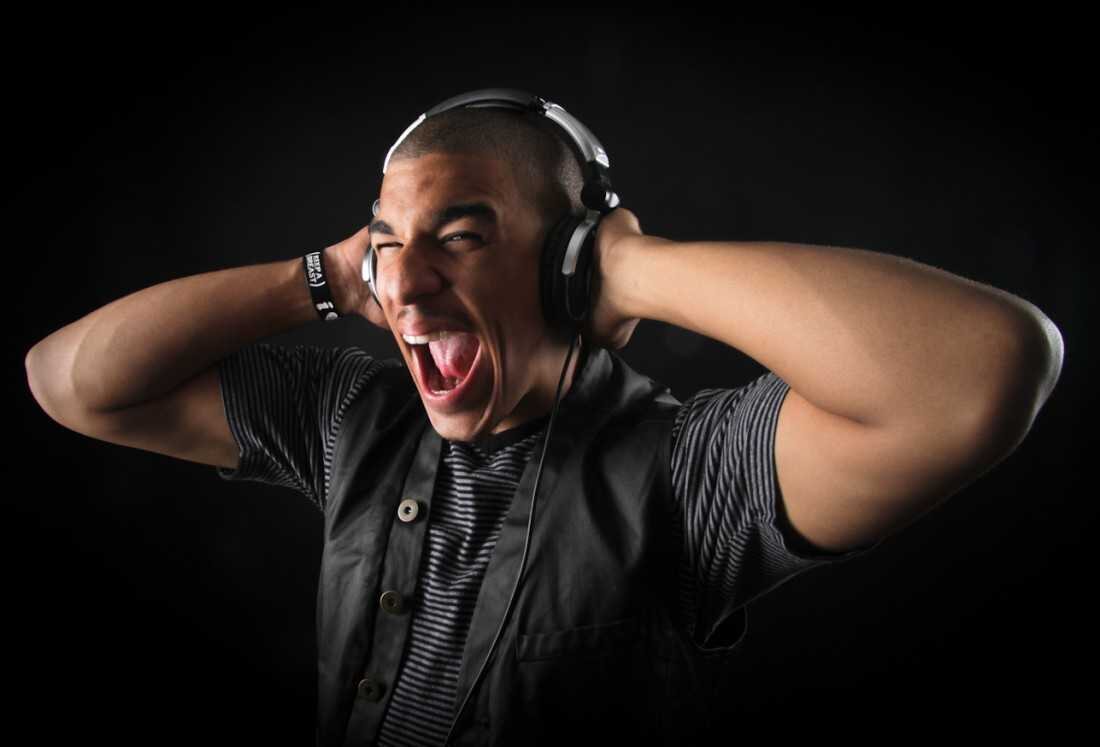 Man in headphones shouting with his hands on his head against a black background